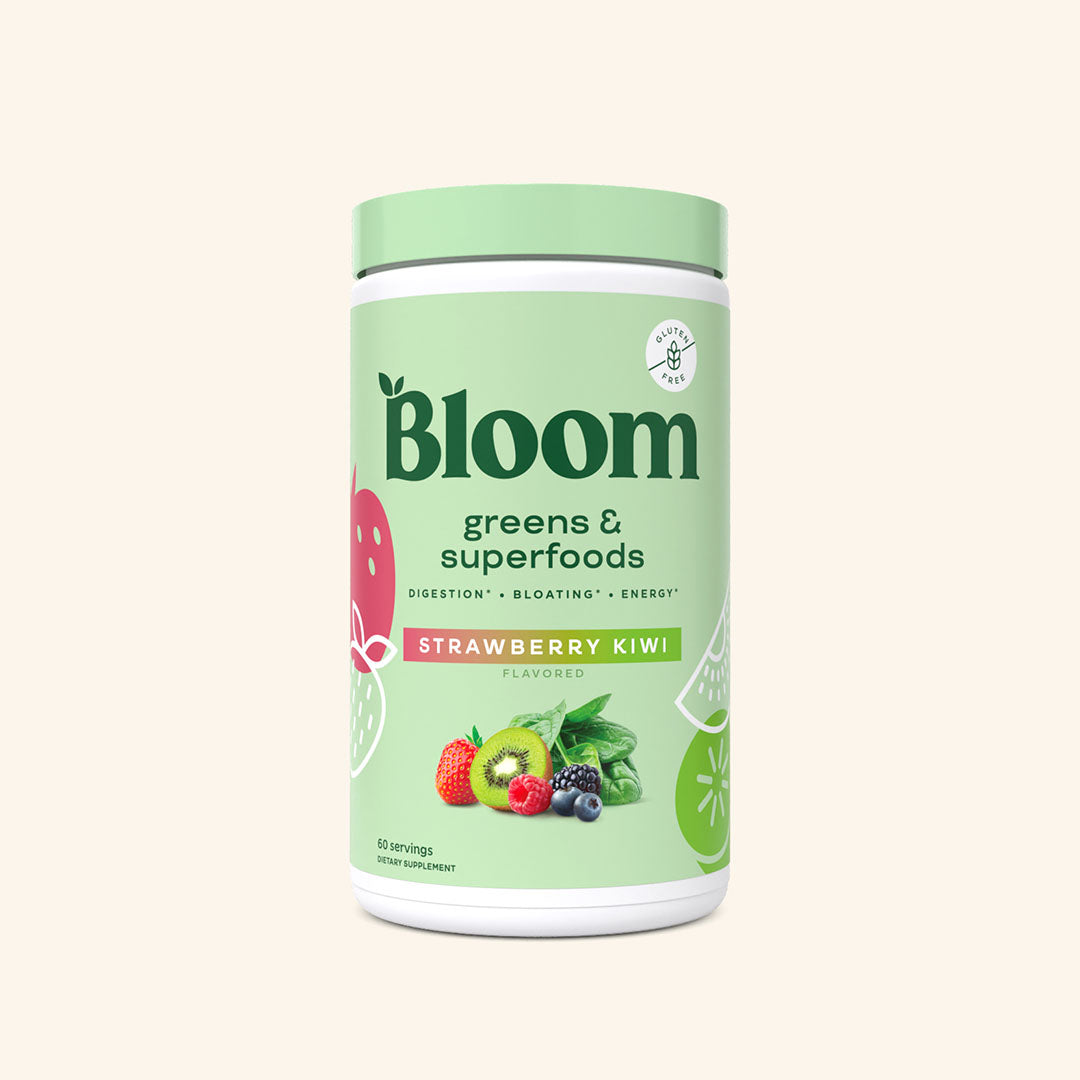 A container of Bloom greens & superfoods powder in Strawberry Kiwi flavor, labeled as supporting digestion, bloating, and energy.
